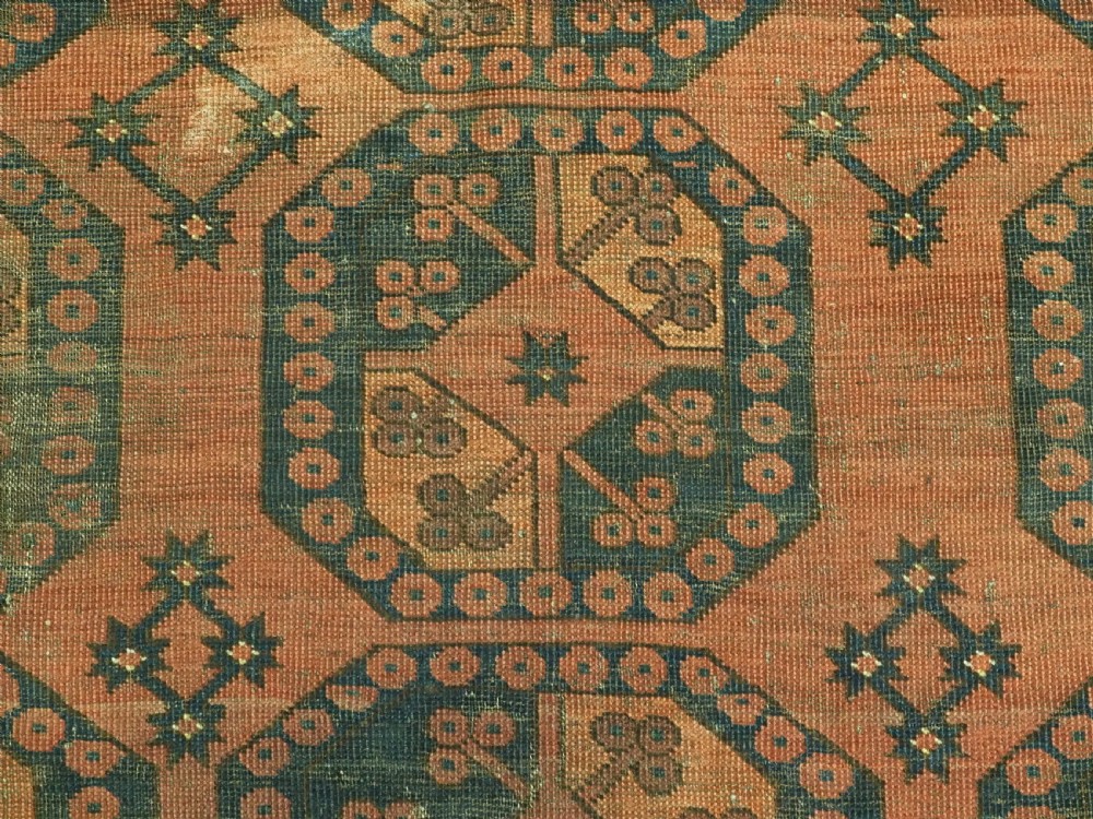 An antique Ersari Turkmen hand-knotted wool carpet displaying repeated octagonal gol motifs on a terracotta field with geometric borders. View X