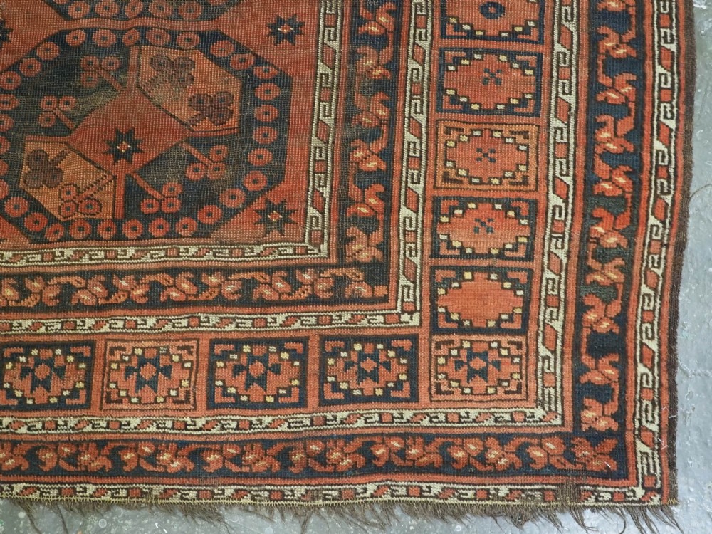An antique Ersari Turkmen hand-knotted wool carpet displaying repeated octagonal gol motifs on a terracotta field with geometric borders. View XII