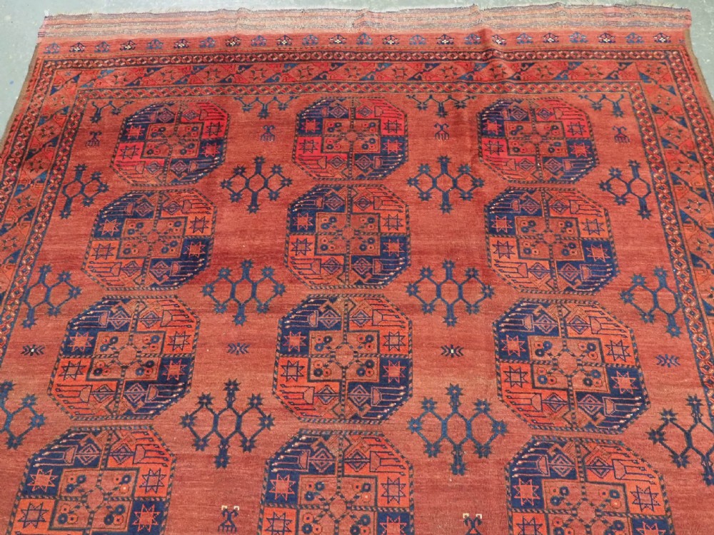 An antique Ersari Turkmen hand-knotted wool main carpet featuring a terracotta red ground filled with dark blue octagonal gul motifs and framed by geometric borders. View III