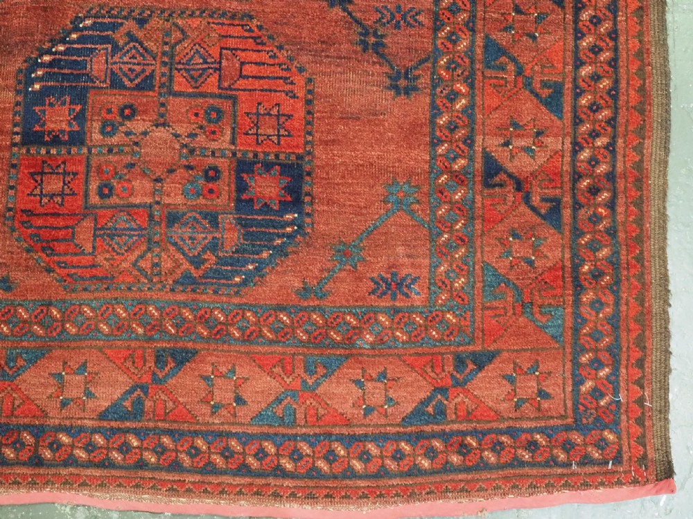 An antique Ersari Turkmen hand-knotted wool main carpet featuring a terracotta red ground filled with dark blue octagonal gul motifs and framed by geometric borders. View VIII