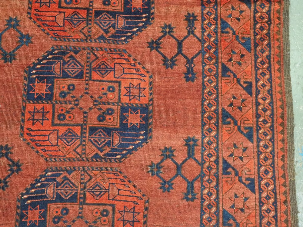 An antique Ersari Turkmen hand-knotted wool main carpet featuring a terracotta red ground filled with dark blue octagonal gul motifs and framed by geometric borders. View IX