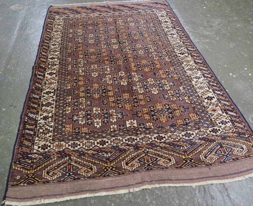 An antique hand-knotted wool carpet featuring repeated diamond-shaped kepse gul motifs across a dark aubergine field, framed by geometric borders. View II
