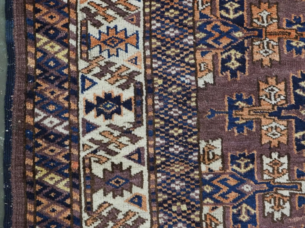 An antique hand-knotted wool carpet featuring repeated diamond-shaped kepse gul motifs across a dark aubergine field, framed by geometric borders. View VII