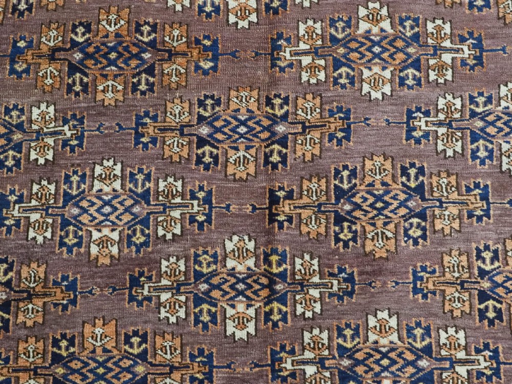 An antique hand-knotted wool carpet featuring repeated diamond-shaped kepse gul motifs across a dark aubergine field, framed by geometric borders. View VIII