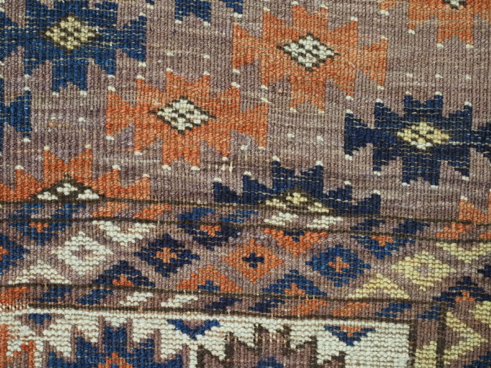 An antique hand-knotted wool carpet featuring repeated diamond-shaped kepse gul motifs across a dark aubergine field, framed by geometric borders. View XIII