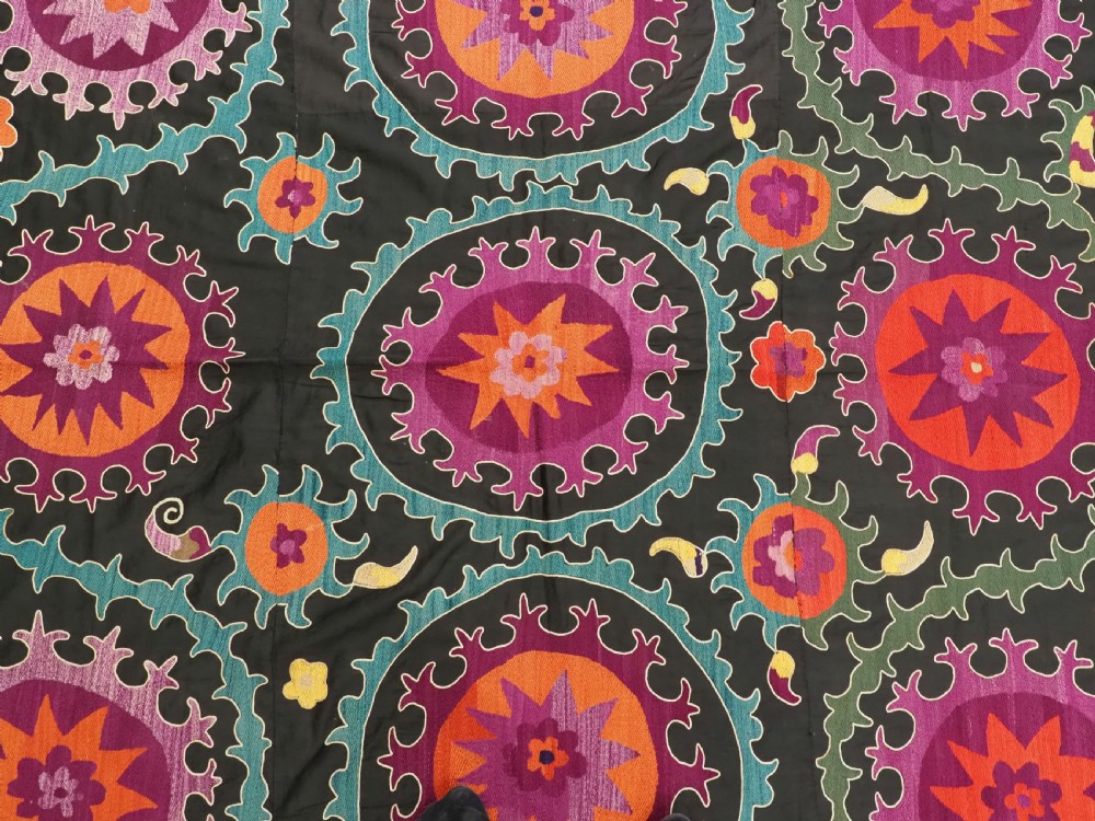 An antique Uzbek suzani textile featuring vibrant purple, orange, and teal silk embroidery in medallion patterns across a black cotton ground. View VIII