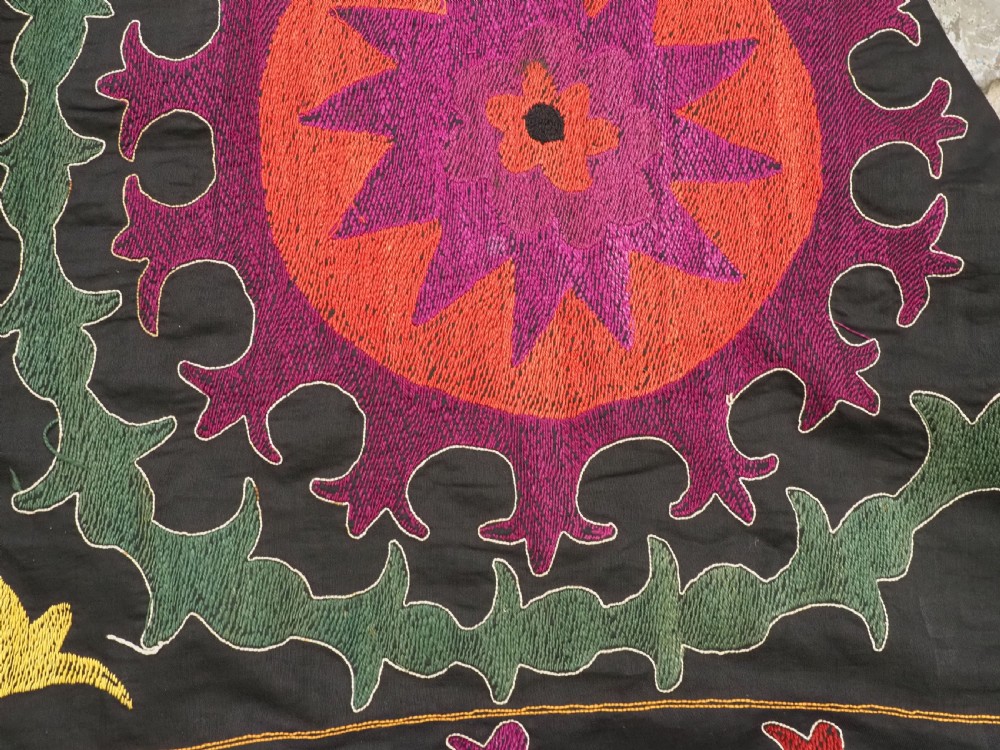An antique Uzbek suzani textile featuring vibrant purple, orange, and teal silk embroidery in medallion patterns across a black cotton ground. View XII