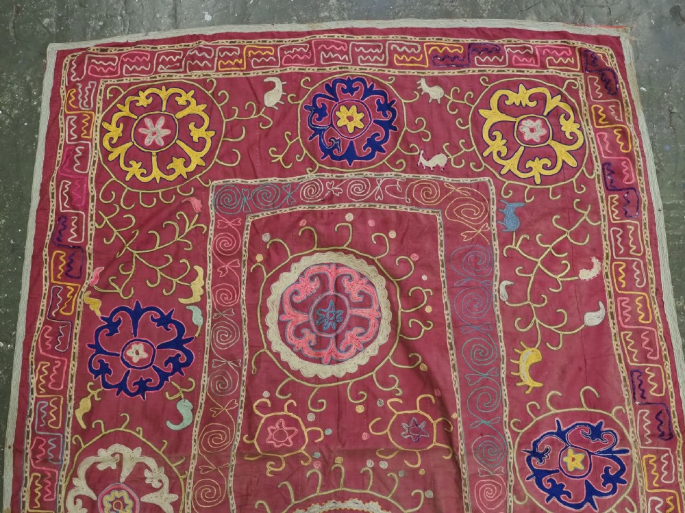 A rectangular magenta pink cotton textile embroidered with circular floral medallions in yellow, blue, and white silk threads. View II