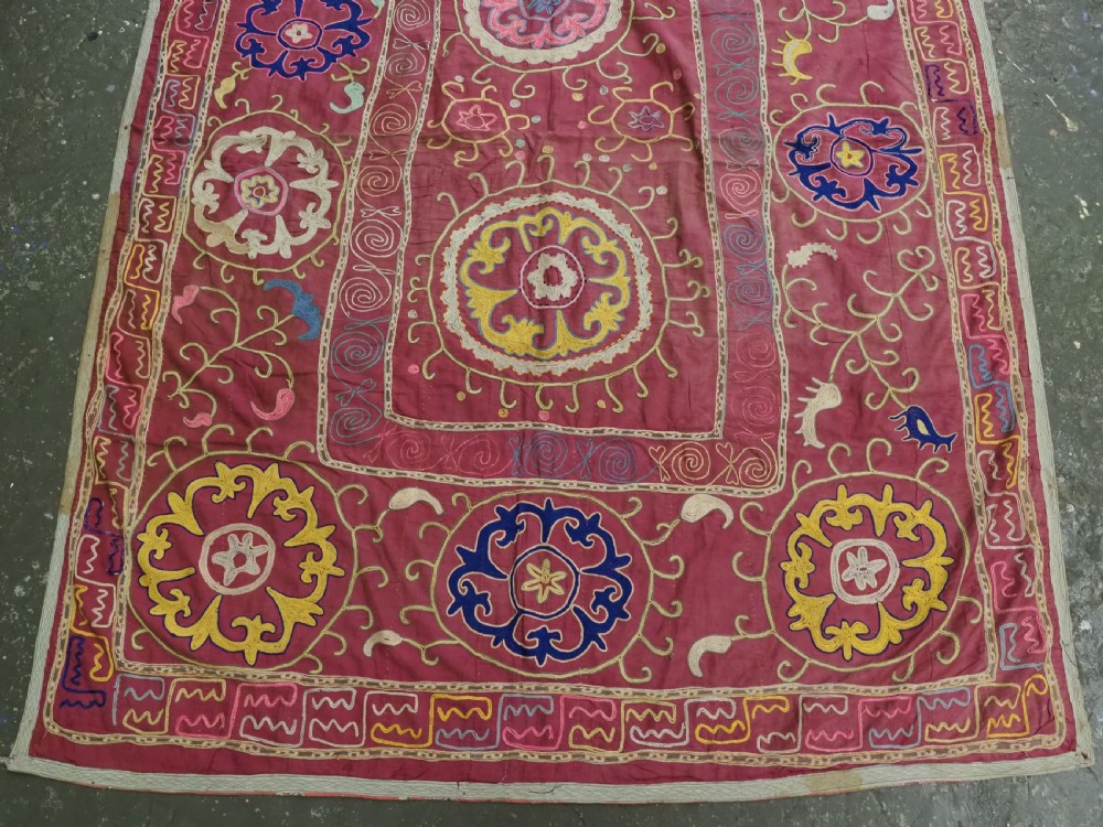 A rectangular magenta pink cotton textile embroidered with circular floral medallions in yellow, blue, and white silk threads. View IV