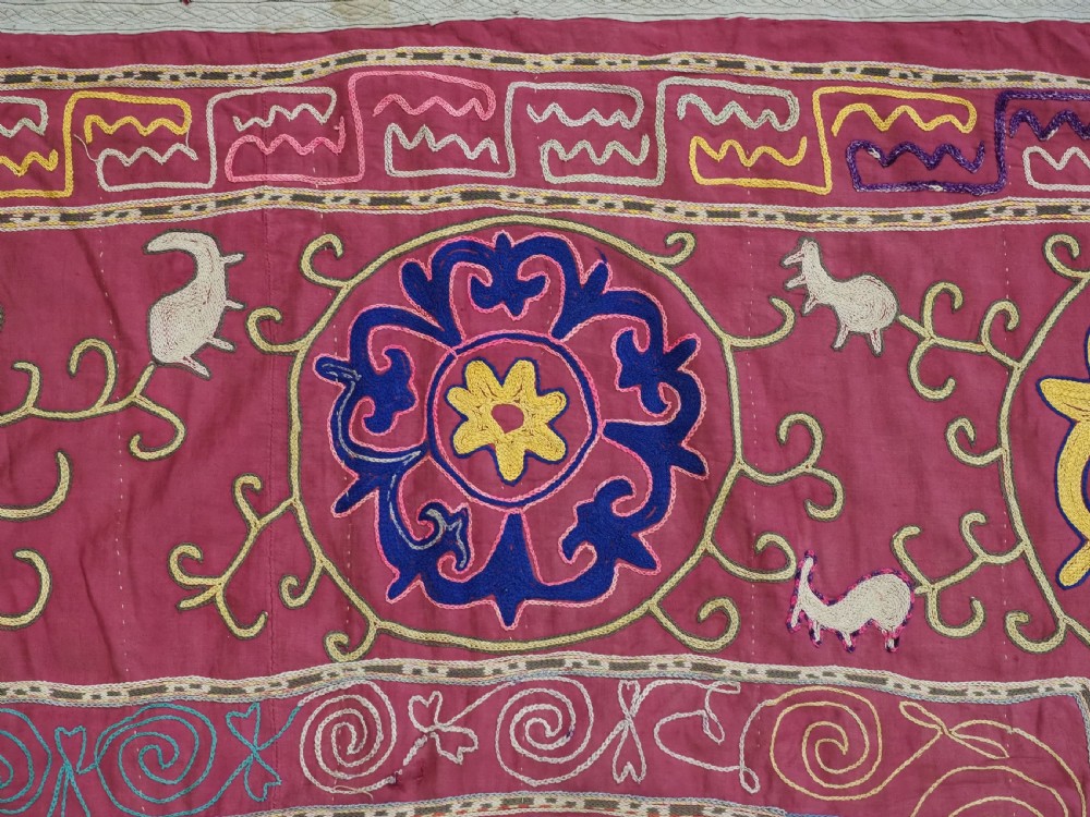 A rectangular magenta pink cotton textile embroidered with circular floral medallions in yellow, blue, and white silk threads. View VII