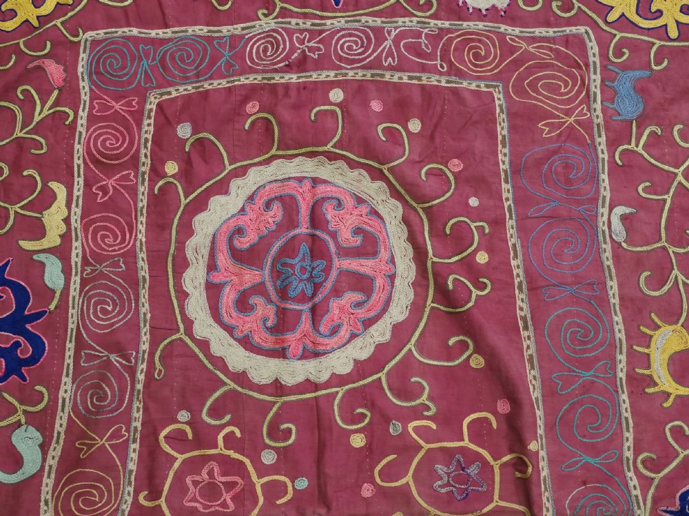 A rectangular magenta pink cotton textile embroidered with circular floral medallions in yellow, blue, and white silk threads. View VIII
