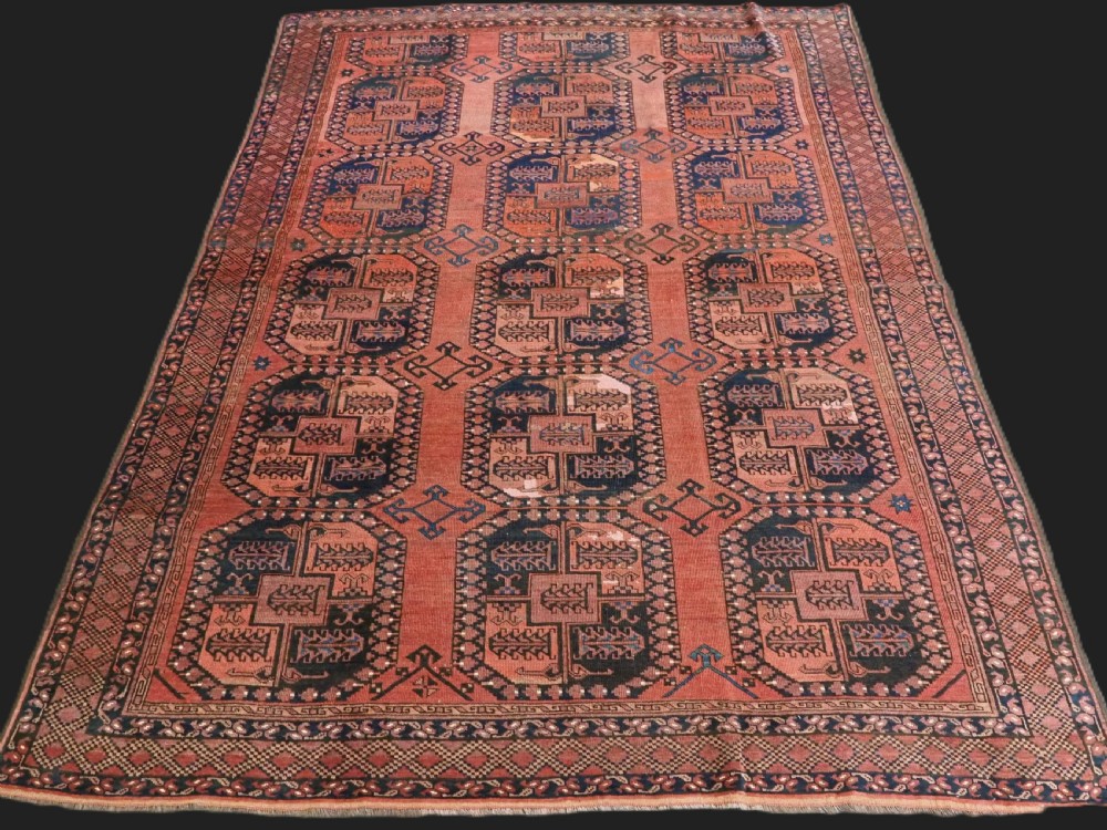 A hand-knotted antique Afghan Ersari Turkmen wool carpet featuring octagonal gul motifs on a rust red ground with geometric borders.