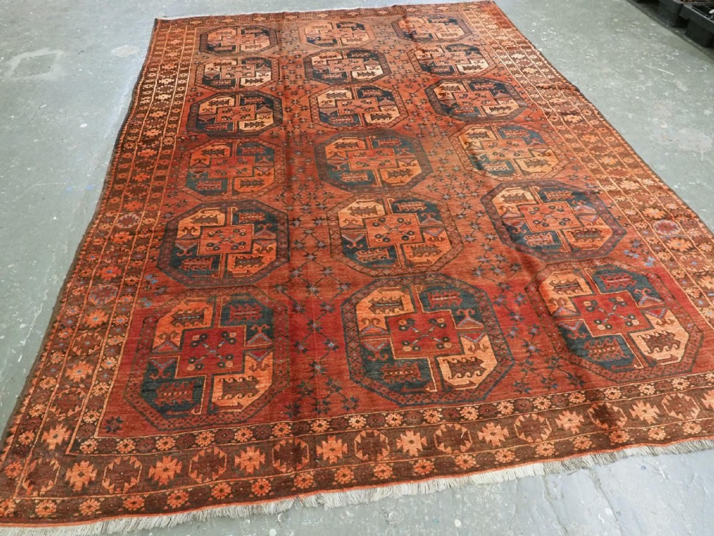 An antique northern Afghan Ersari Turkmen wool carpet featuring repeating octagonal gul motifs in dark blue, beige, and brown set against a deep terracotta red field. View II
