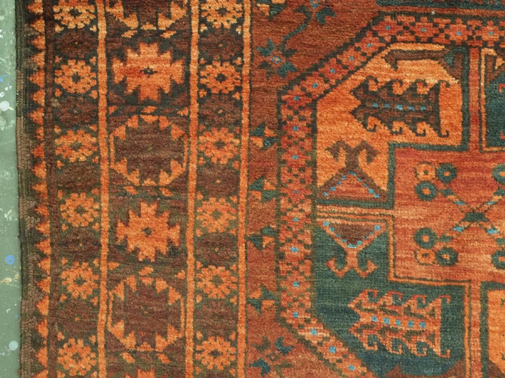 An antique northern Afghan Ersari Turkmen wool carpet featuring repeating octagonal gul motifs in dark blue, beige, and brown set against a deep terracotta red field. View VII