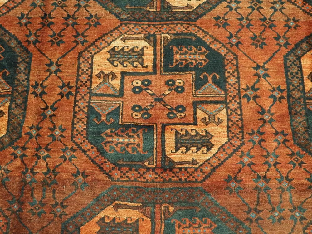 An antique northern Afghan Ersari Turkmen wool carpet featuring repeating octagonal gul motifs in dark blue, beige, and brown set against a deep terracotta red field. View IX