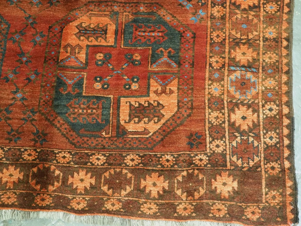 An antique northern Afghan Ersari Turkmen wool carpet featuring repeating octagonal gul motifs in dark blue, beige, and brown set against a deep terracotta red field. View XI