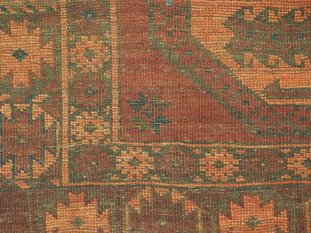 An antique northern Afghan Ersari Turkmen wool carpet featuring repeating octagonal gul motifs in dark blue, beige, and brown set against a deep terracotta red field. View XII