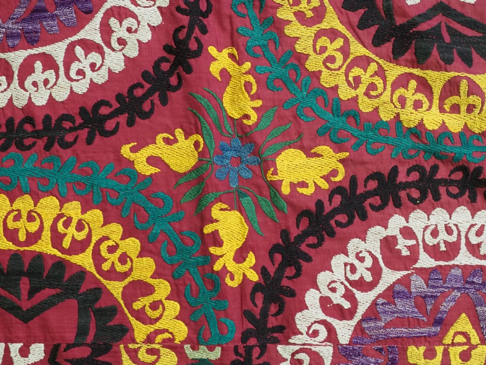 A rectangular hand-embroidered Uzbek suzani textile featuring circular solar medallions with central stars in shades of yellow, purple, white, and red. View VIII