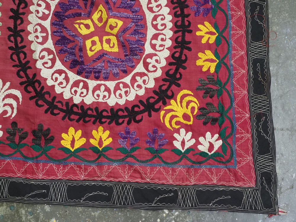 A rectangular hand-embroidered Uzbek suzani textile featuring circular solar medallions with central stars in shades of yellow, purple, white, and red. View XI
