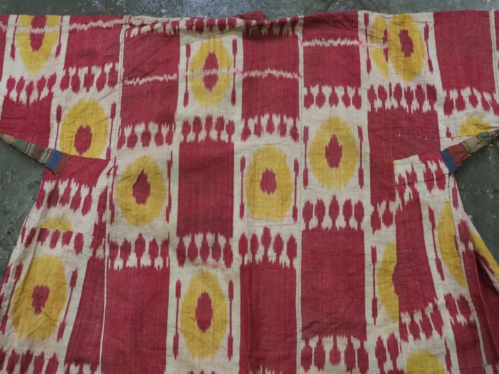 An antique T-shaped Uzbek silk ikat robe featuring geometric motifs in magenta, yellow, and off-white. View III