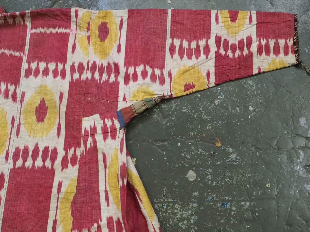 An antique T-shaped Uzbek silk ikat robe featuring geometric motifs in magenta, yellow, and off-white. View V