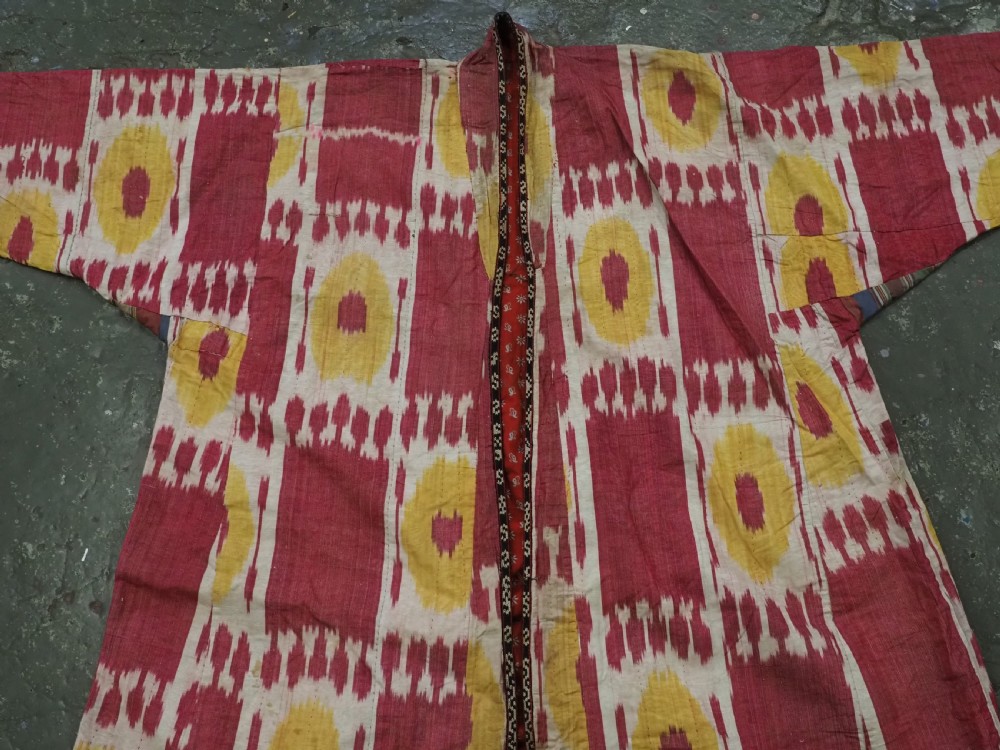 An antique T-shaped Uzbek silk ikat robe featuring geometric motifs in magenta, yellow, and off-white. View X