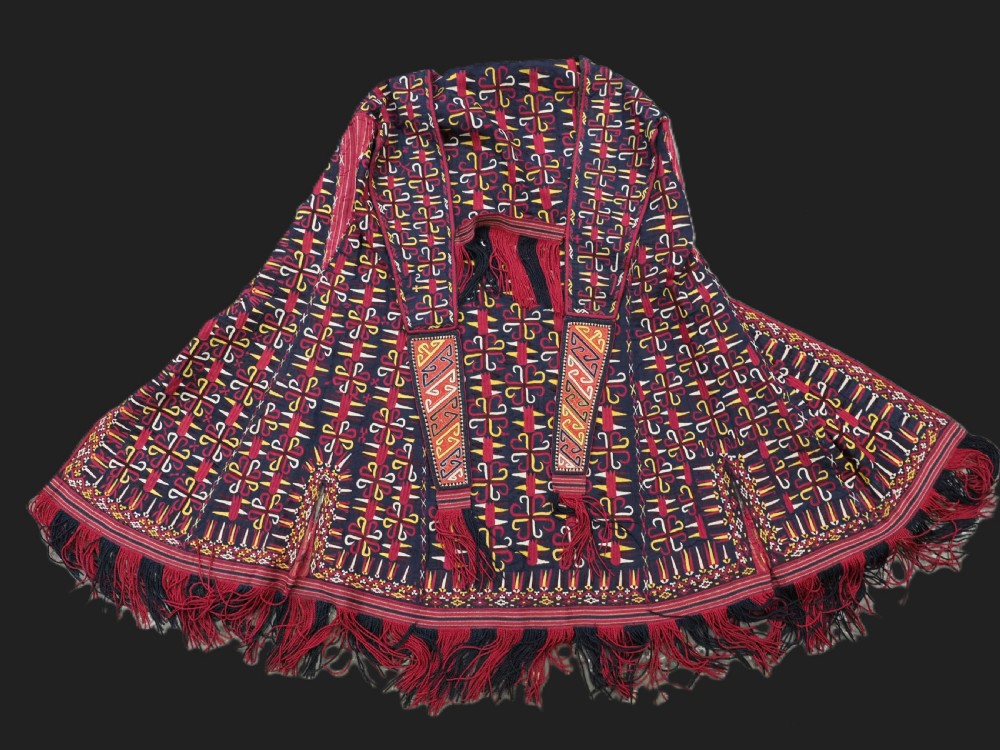 An antique 19th-century Turkmen chyrpy ceremonial coat featuring dense red, yellow, and white silk hand embroidery on a dark base with fringed borders.
