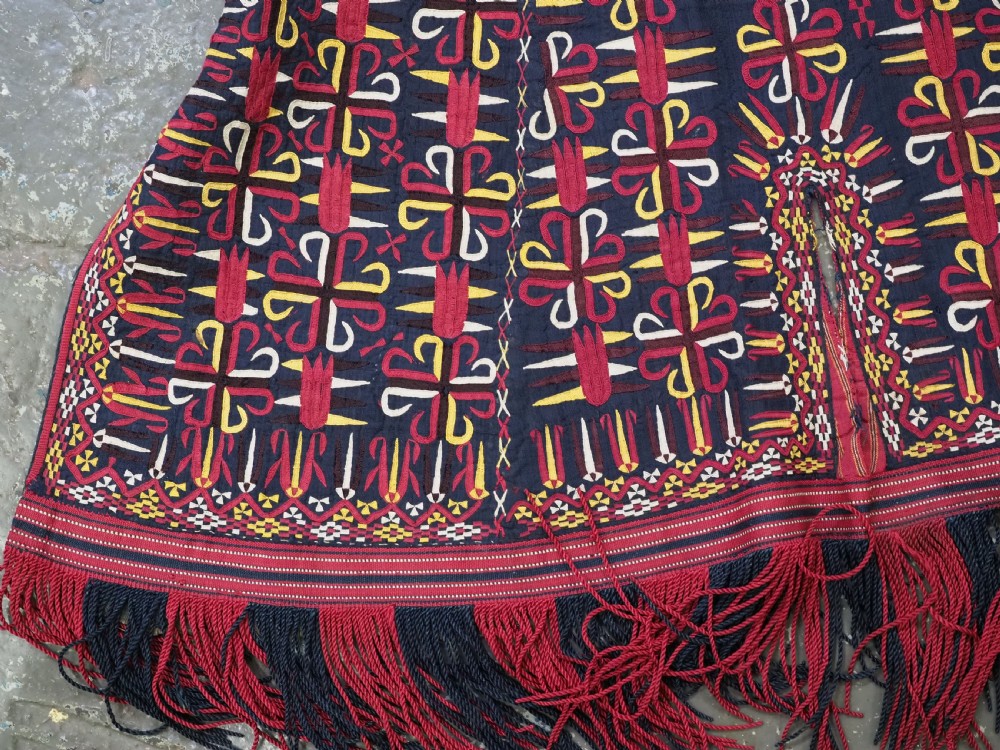 An antique 19th-century Turkmen chyrpy ceremonial coat featuring dense red, yellow, and white silk hand embroidery on a dark base with fringed borders. View V