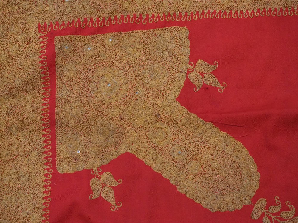 A rectangular red wool shawl with extensive gold-coloured needlework along the borders and corner motifs. View VII