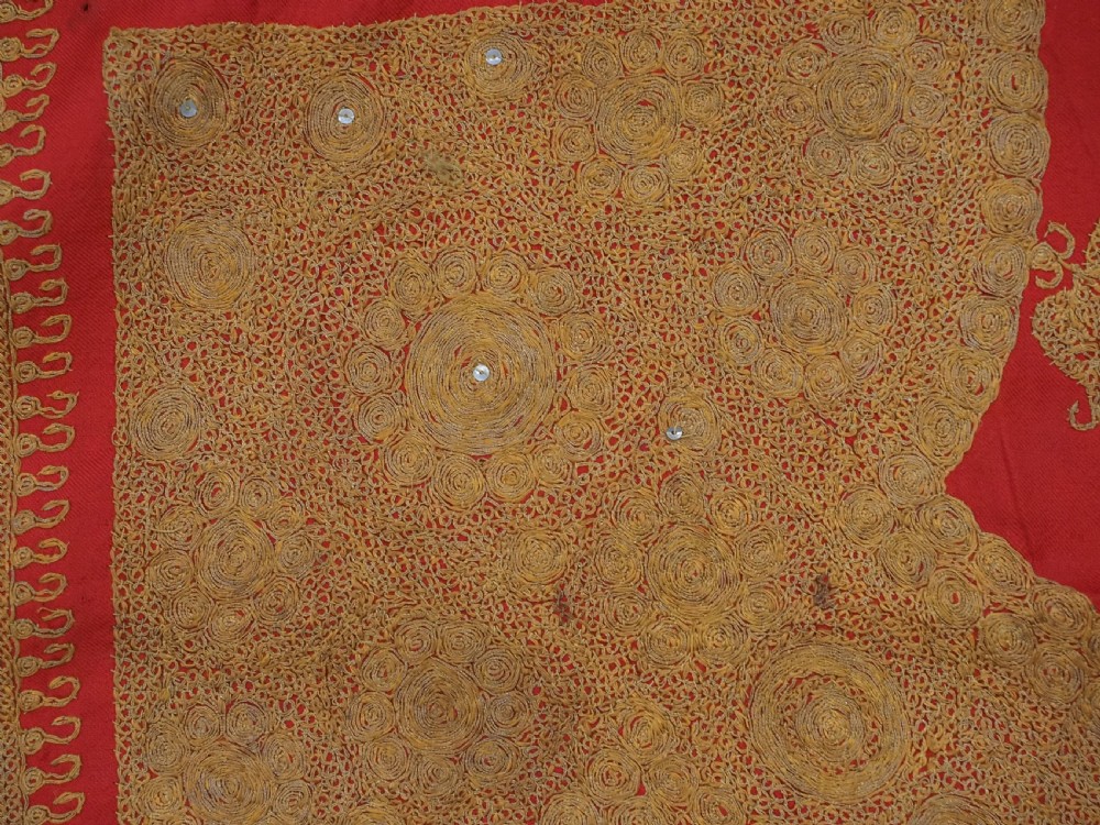 A rectangular red wool shawl with extensive gold-coloured needlework along the borders and corner motifs. View VIII
