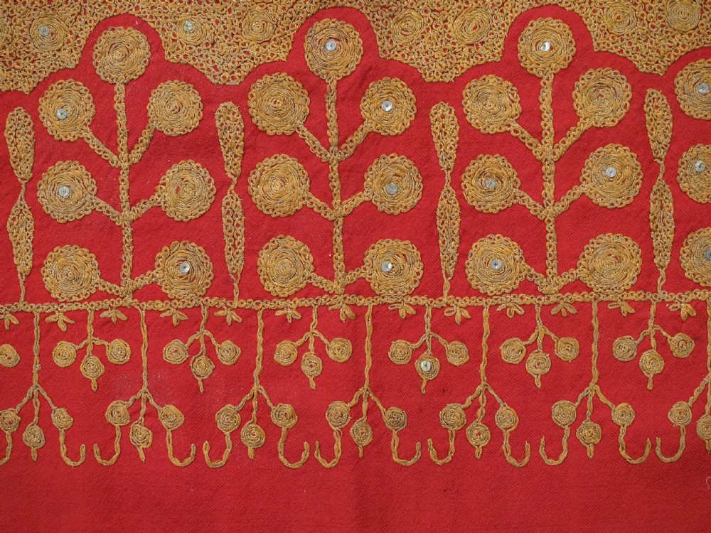 A rectangular red wool shawl with extensive gold-coloured needlework along the borders and corner motifs. View XIV