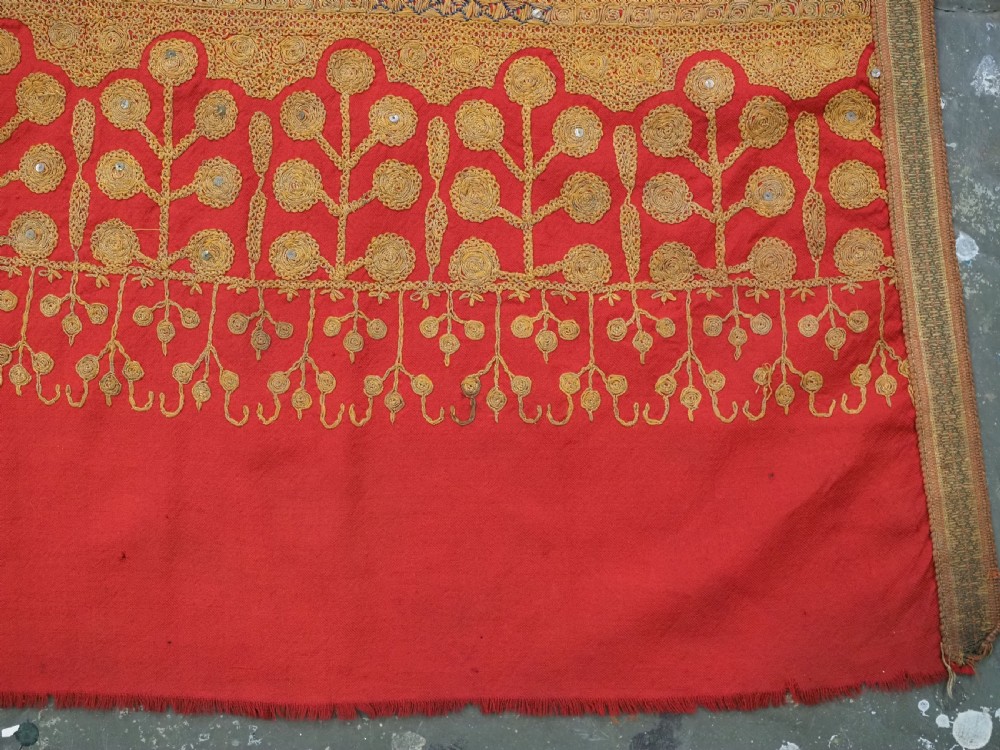 A rectangular red wool shawl with extensive gold-coloured needlework along the borders and corner motifs. View XV
