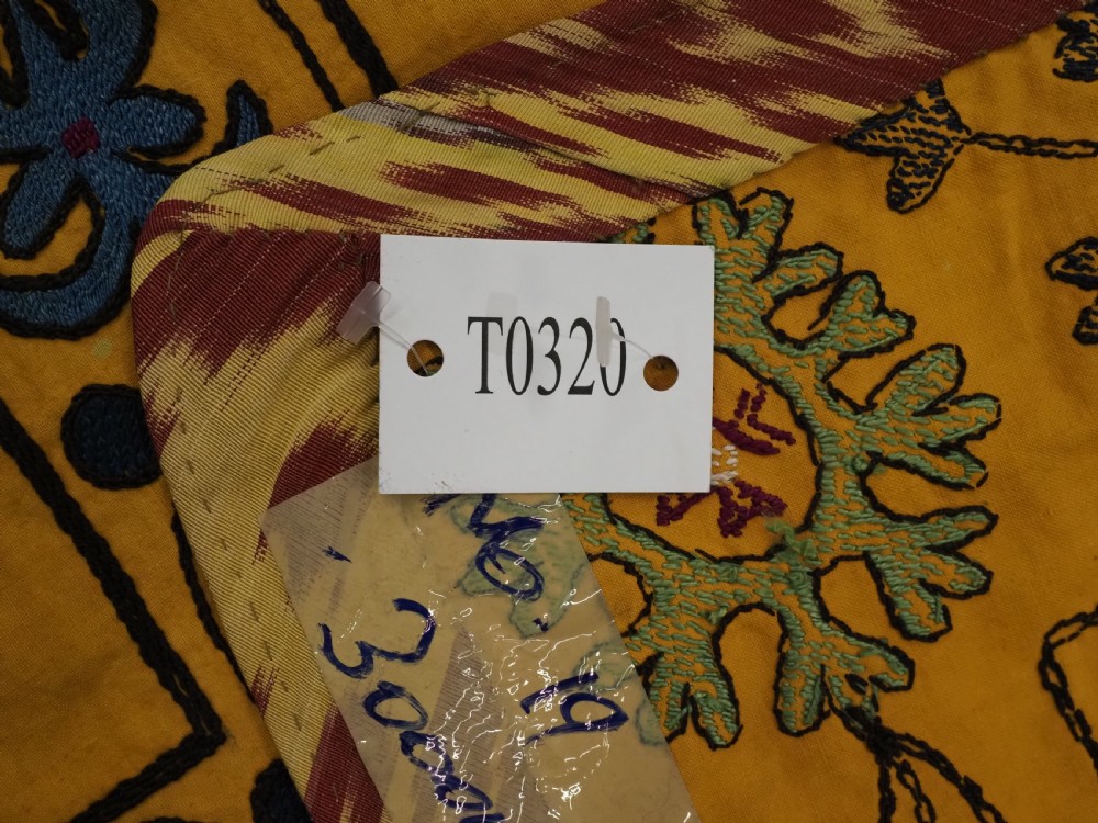 A rectangular yellow cotton textile featuring hand-embroidered silk floral medallions, vines, and circular motifs in blue, green, and burgundy. View VIII