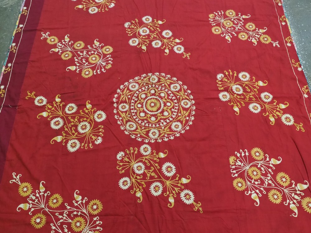 A rectangular red adras silk and cotton textile featuring yellow and white silk thread embroidery with a central circular floral medallion, surrounding floral sprays, and a matching decorative border. View III