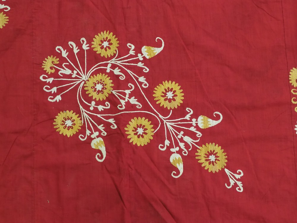 A rectangular red adras silk and cotton textile featuring yellow and white silk thread embroidery with a central circular floral medallion, surrounding floral sprays, and a matching decorative border. View IX