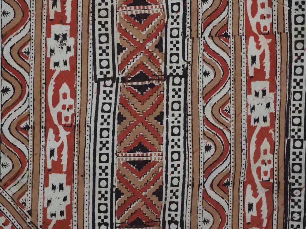 A rectangular red wool textile featuring multi-coloured silk embroidery with central circular medallions and decorative botanical borders. View X