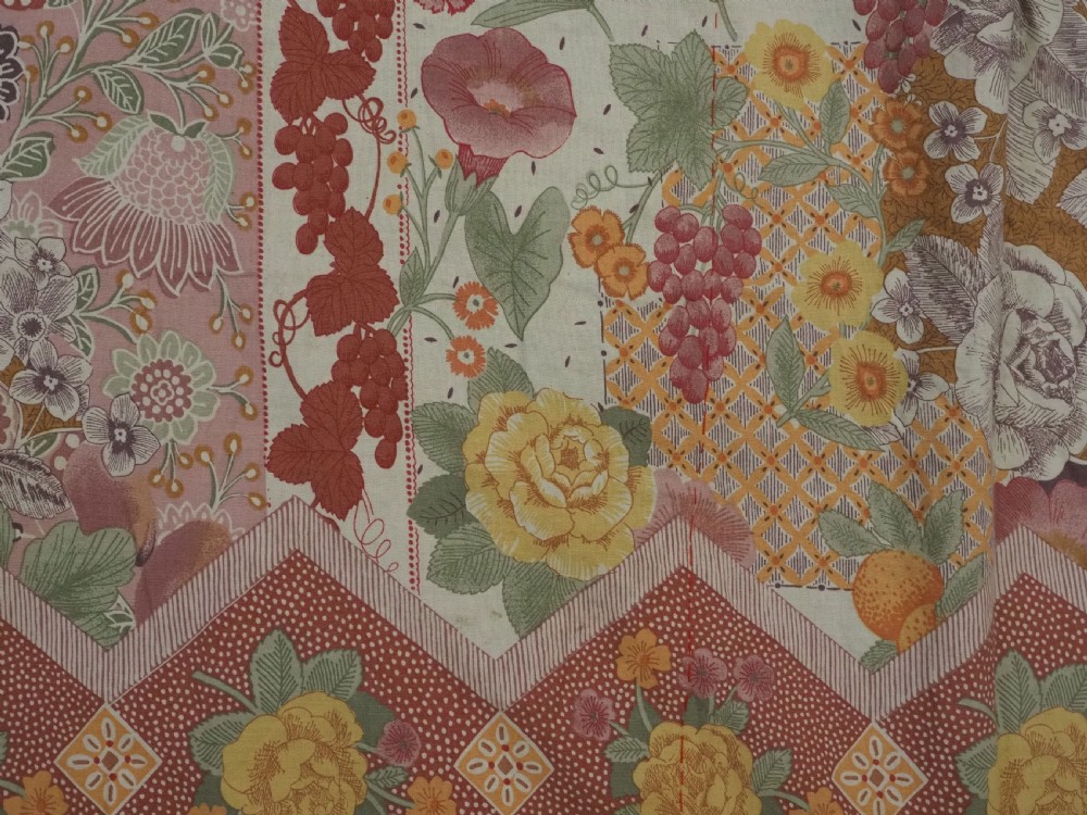 An antique rectangular red cotton suzani textile featuring hand embroidery in silk with floral rosettes and botanical motifs in white, yellow, green, and blue. View XI