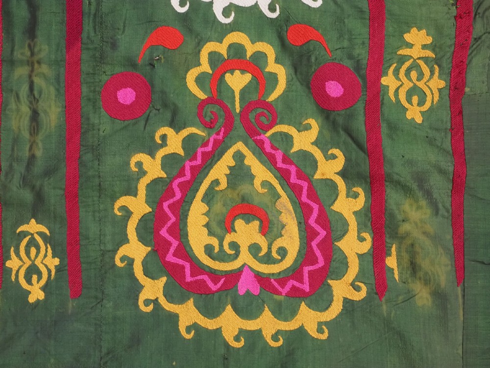 An antique green silk suzani bed cover featuring a plain central panel surrounded by a broad embroidered border with magenta, yellow, and white floral motifs. View IX