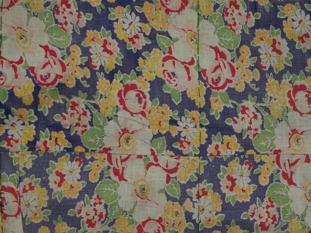 An antique green silk suzani bed cover featuring a plain central panel surrounded by a broad embroidered border with magenta, yellow, and white floral motifs. View X