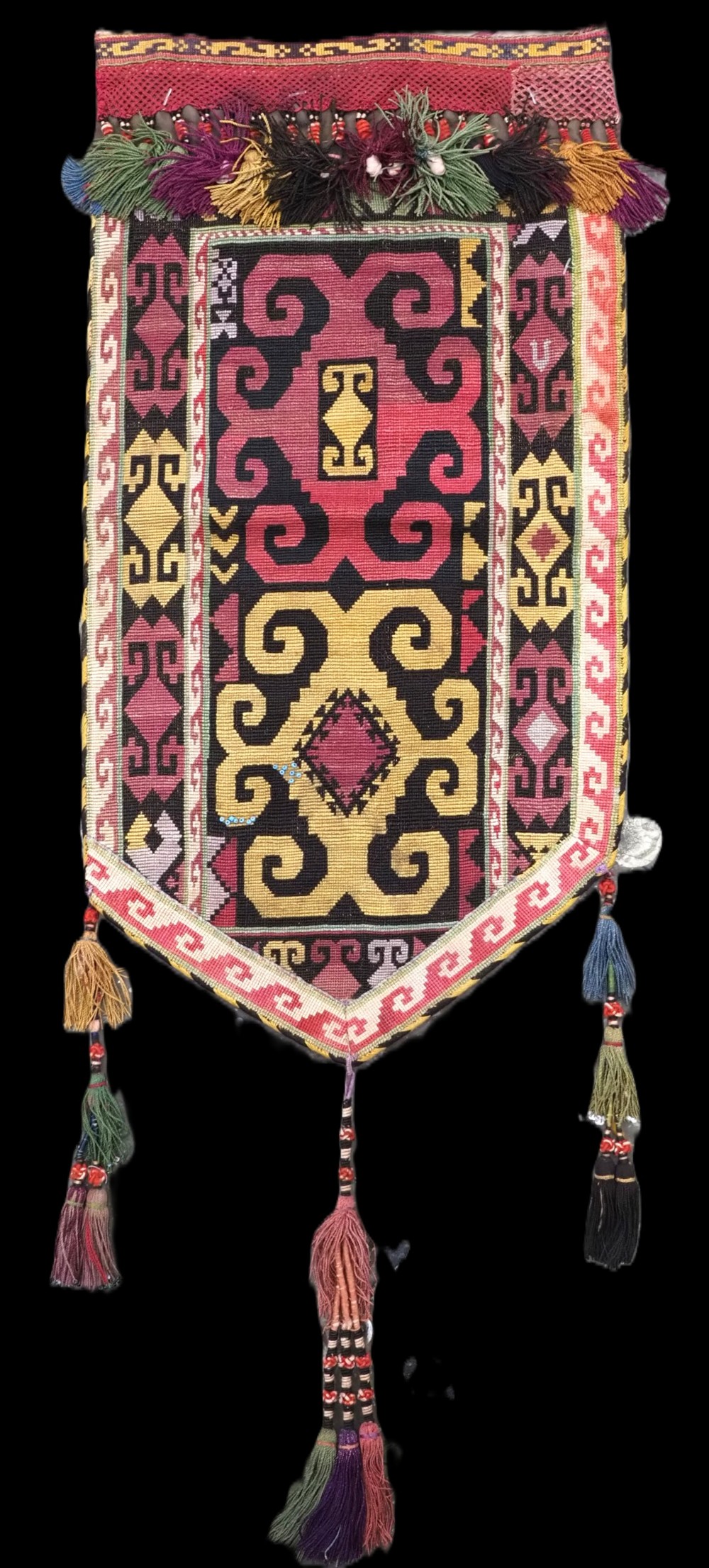 An antique Uzbek Lakai hand-embroidered wool textile featuring geometric horn motifs, a pointed lower hem, and multi-coloured yarn tassels.