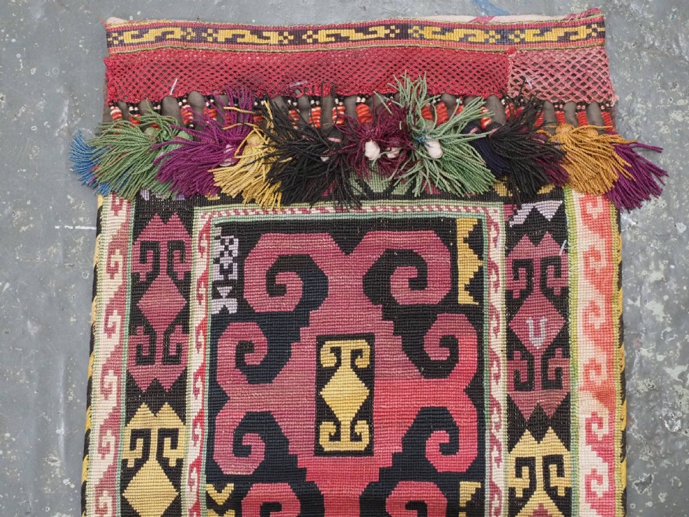An antique Uzbek Lakai hand-embroidered wool textile featuring geometric horn motifs, a pointed lower hem, and multi-coloured yarn tassels. View III