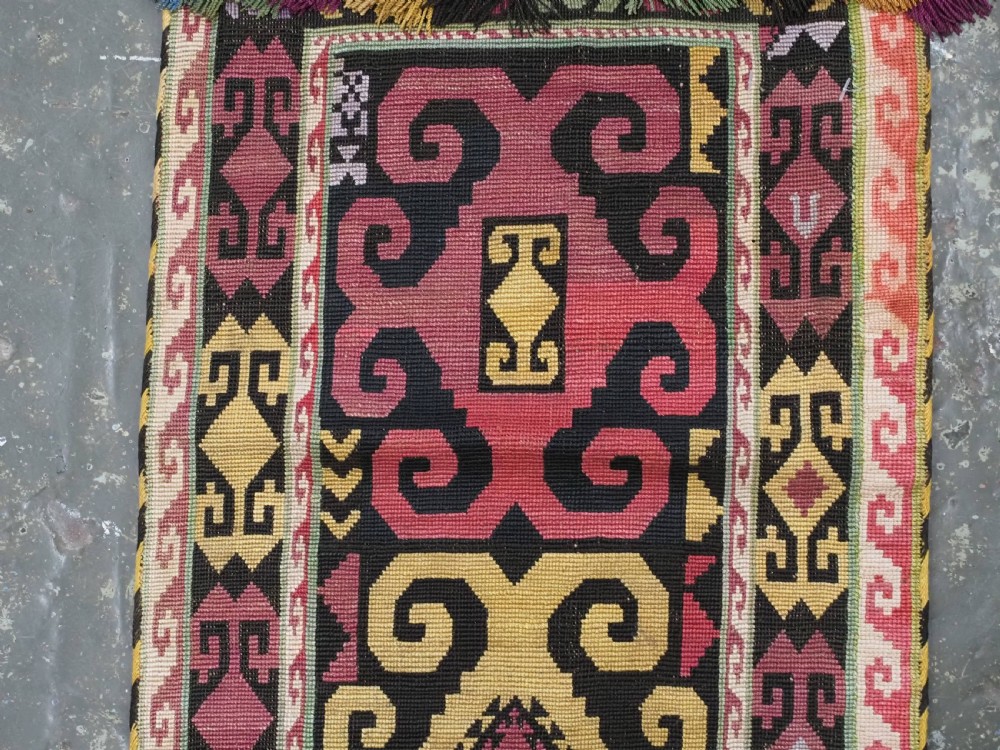 An antique Uzbek Lakai hand-embroidered wool textile featuring geometric horn motifs, a pointed lower hem, and multi-coloured yarn tassels. View IV