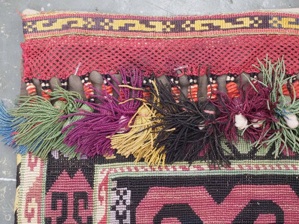 An antique Uzbek Lakai hand-embroidered wool textile featuring geometric horn motifs, a pointed lower hem, and multi-coloured yarn tassels. View VI