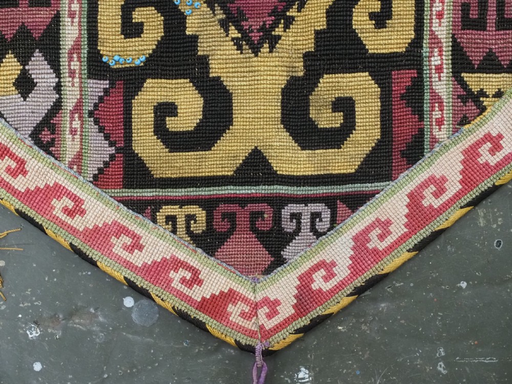 An antique Uzbek Lakai hand-embroidered wool textile featuring geometric horn motifs, a pointed lower hem, and multi-coloured yarn tassels. View VIII
