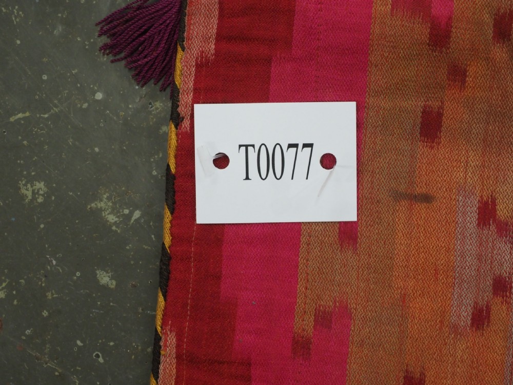 An antique Uzbek Lakai hand-embroidered wool textile featuring geometric horn motifs, a pointed lower hem, and multi-coloured yarn tassels. View X