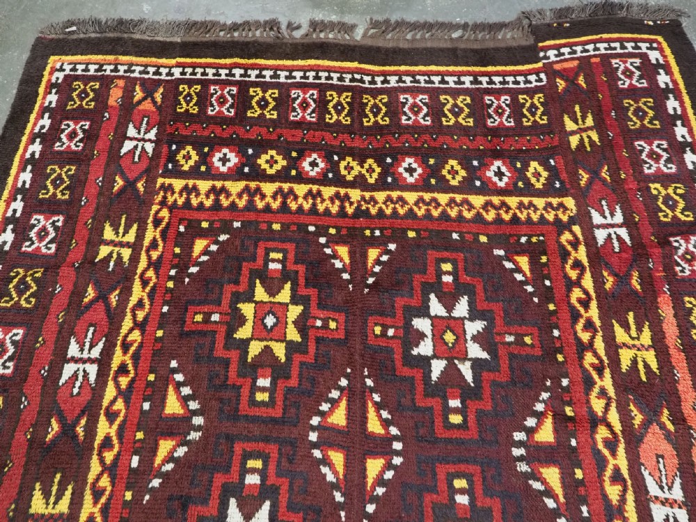 An antique handwoven Uzbek Julkyrs rug with geometric star motifs constructed from four vertical wool strips stitched together in tones of brown, red, and yellow. View III