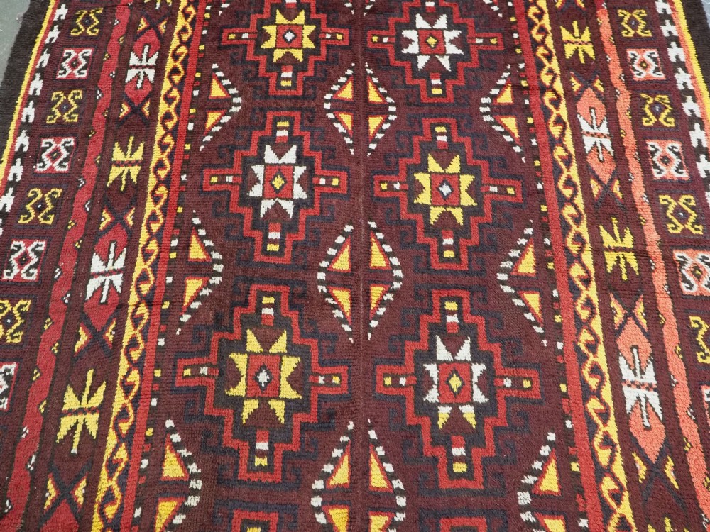 An antique handwoven Uzbek Julkyrs rug with geometric star motifs constructed from four vertical wool strips stitched together in tones of brown, red, and yellow. View IV