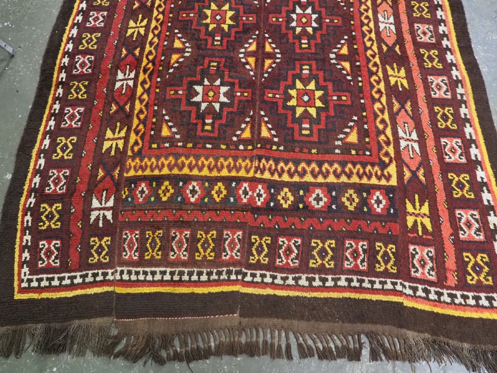 An antique handwoven Uzbek Julkyrs rug with geometric star motifs constructed from four vertical wool strips stitched together in tones of brown, red, and yellow. View VI