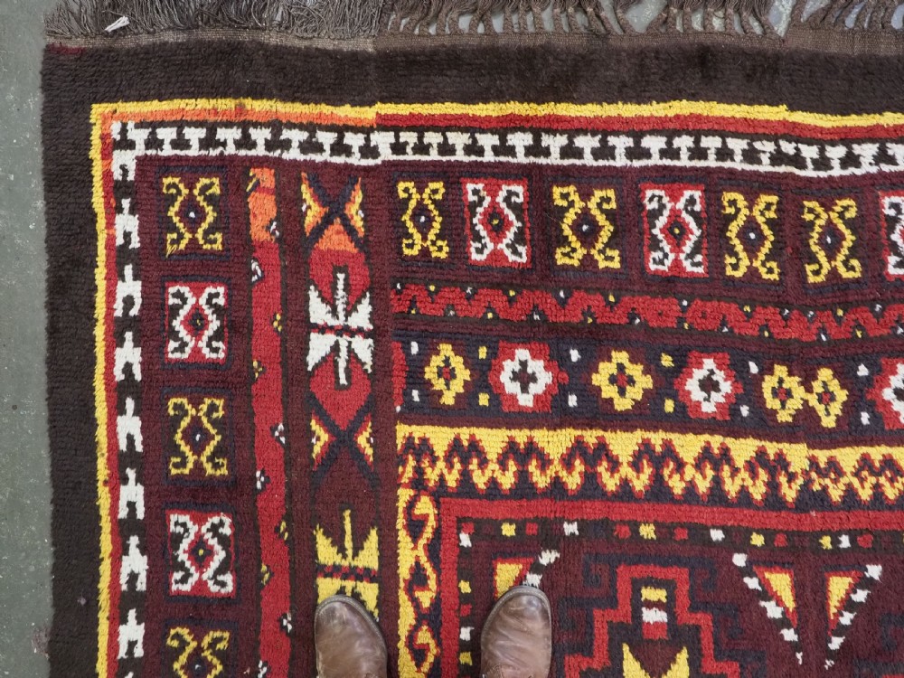 An antique handwoven Uzbek Julkyrs rug with geometric star motifs constructed from four vertical wool strips stitched together in tones of brown, red, and yellow. View VII