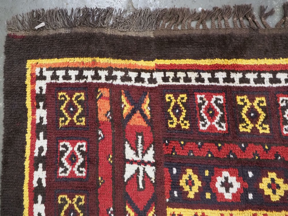 An antique handwoven Uzbek Julkyrs rug with geometric star motifs constructed from four vertical wool strips stitched together in tones of brown, red, and yellow. View VIII